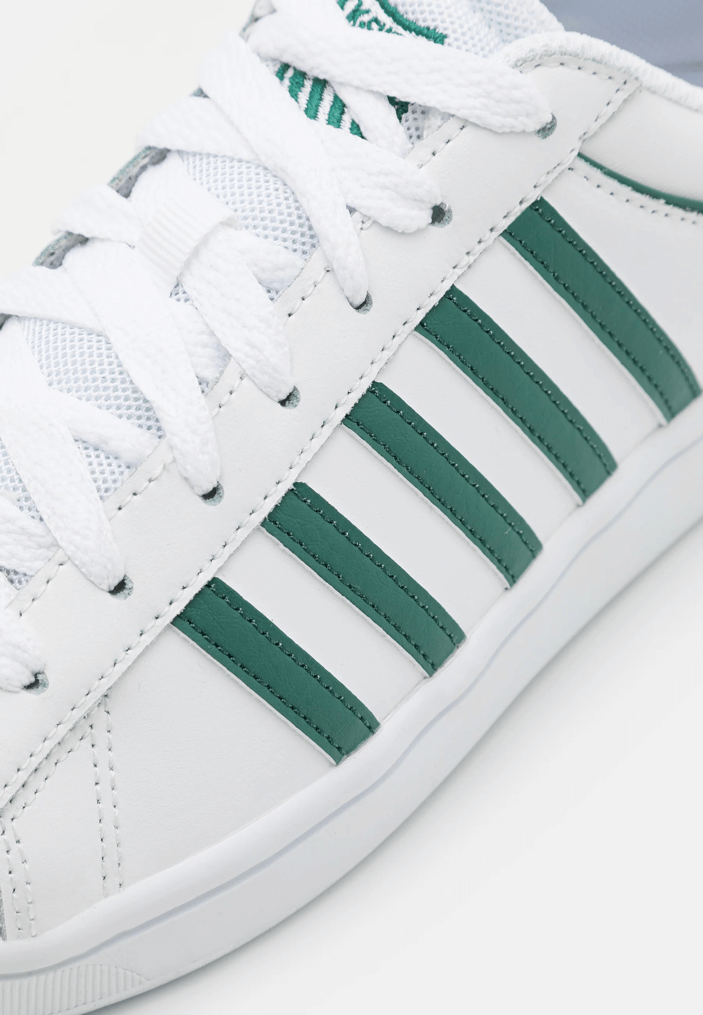 Sneakers bianco verde in pelle con dettagli verdi sulle strisce laterali e suola bianca.