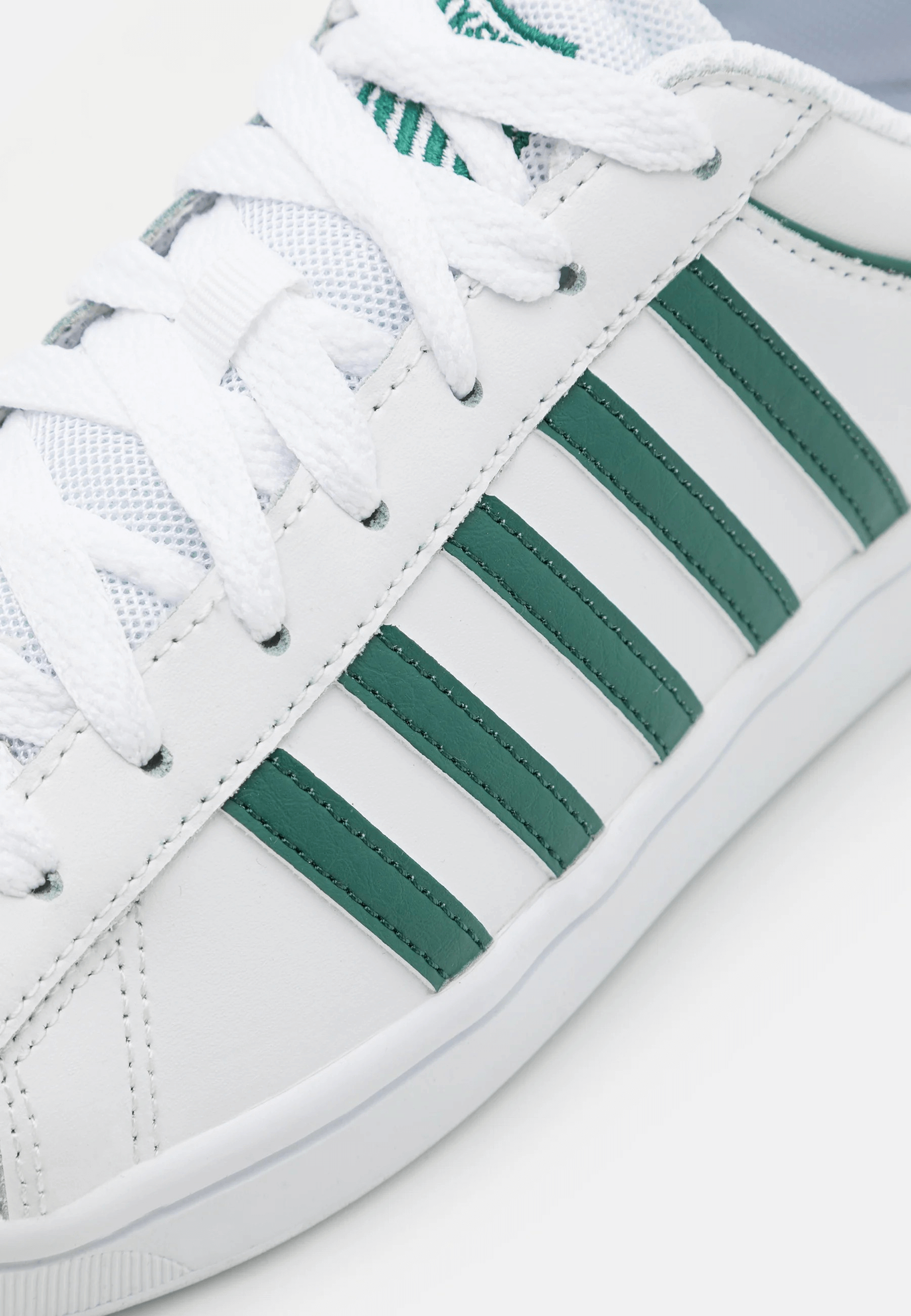 Sneakers bianco verde in pelle con dettagli verdi sulle strisce laterali e suola bianca.